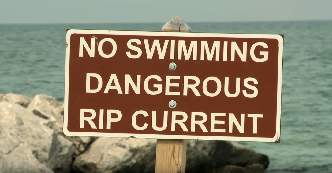 A sign by the water states: No swimming. Dangerous Rip Current.